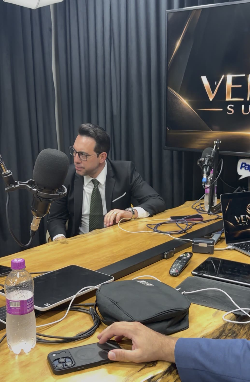 Empresário de terno escuro ouvindo atentamente à mesa do estúdio